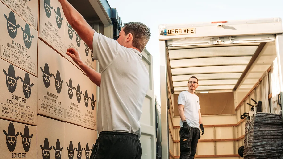 A Bearded Bros crew loading a customer's belongings into a removals truck on a Peacehaven residential street near the Meridian Centre