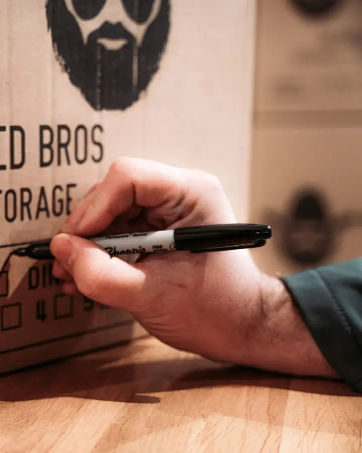 Hand labelling a Bearded Bros moving box by room, ready for a house removal