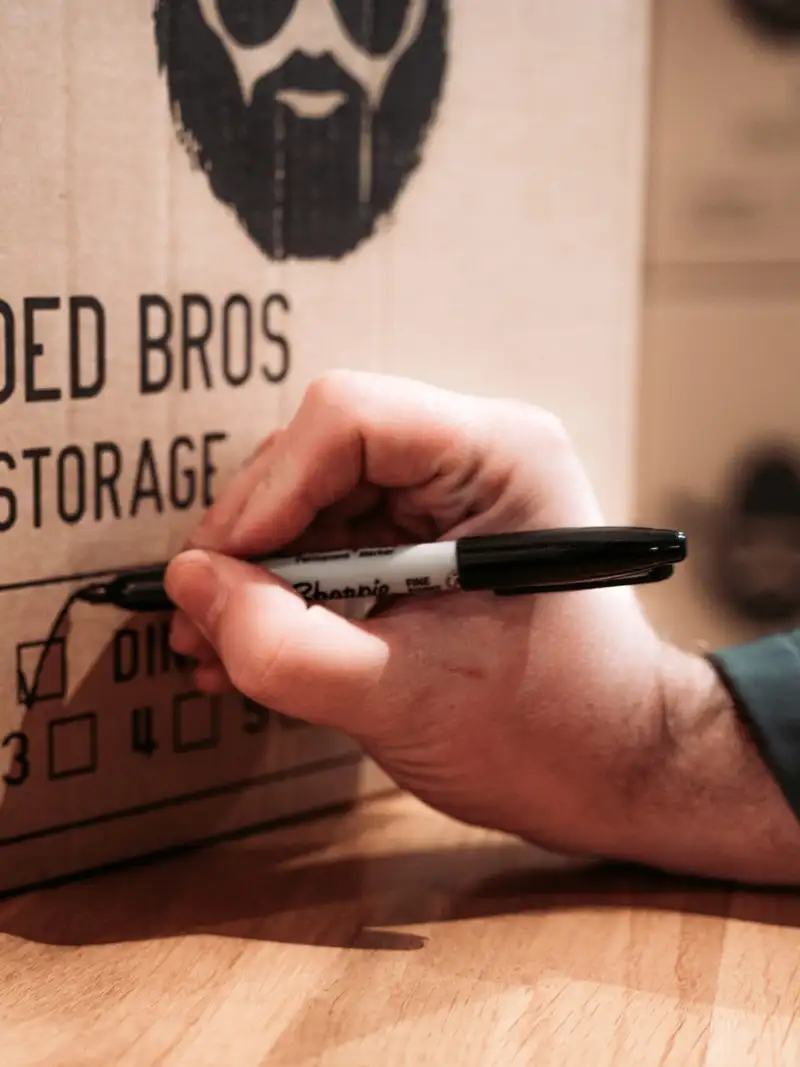 Bearded Bros crew member labelling a packing box by room for a Brighton removal