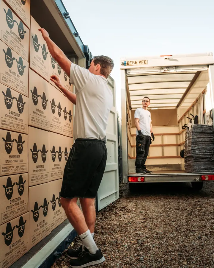 Bearded Bros crew loading branded boxes into a storage container beside a removals van