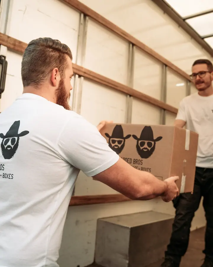 Two Bearded Bros crew members passing a branded box inside a removals van