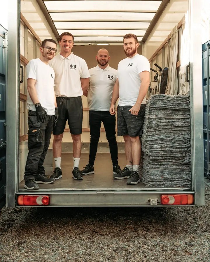 Four Bearded Bros crew members smiling at the back of an open branded van