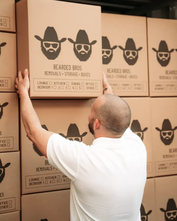 Bearded Bros crew member stacking a branded box against a wall of boxes