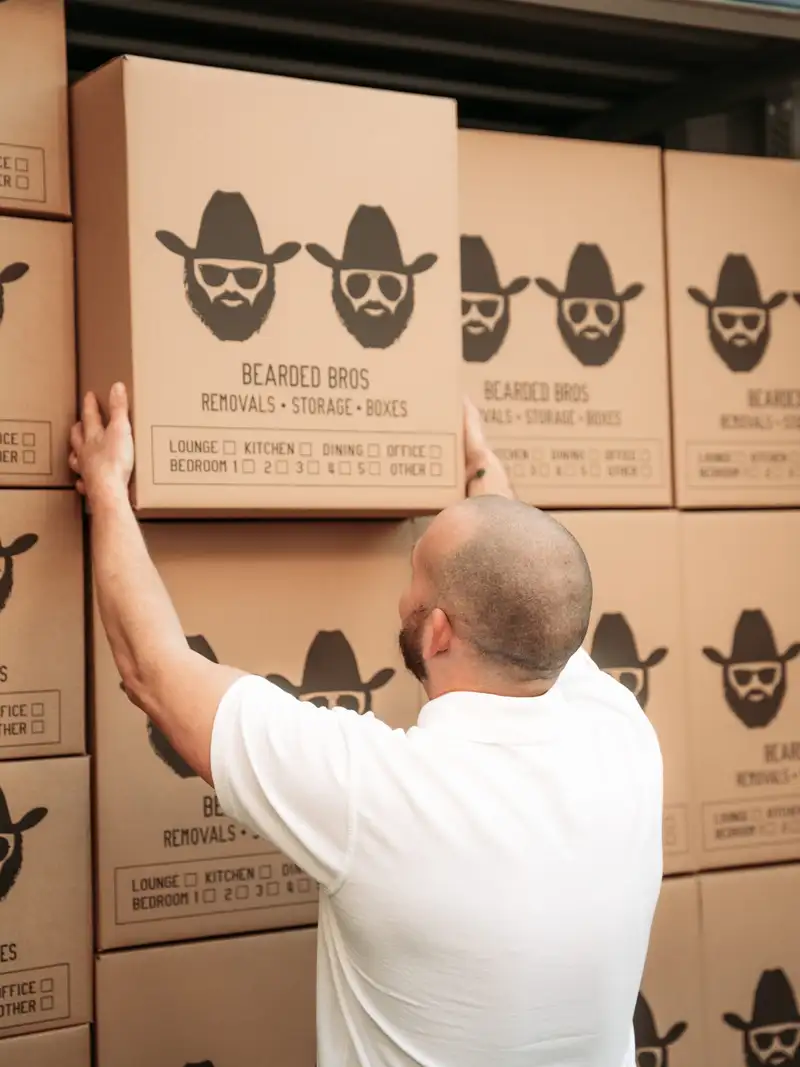 Bearded Bros crew member loading branded boxes into a storage container, close view