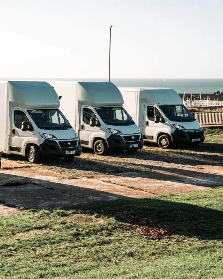 Bearded Bros removals van fleet parked on grass overlooking the Brighton coastline