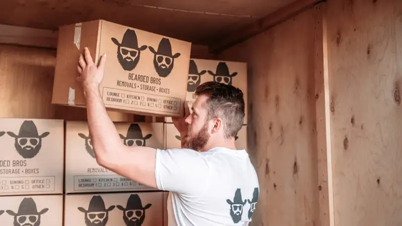 Bearded Bros crew member stacking a branded storage box inside a wooden storage crate