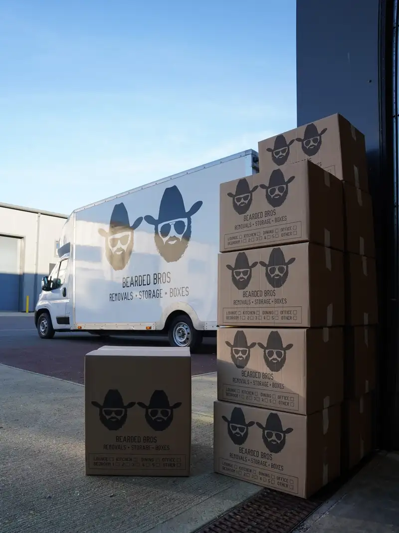 Stacked Bearded Bros branded storage boxes beside removals van