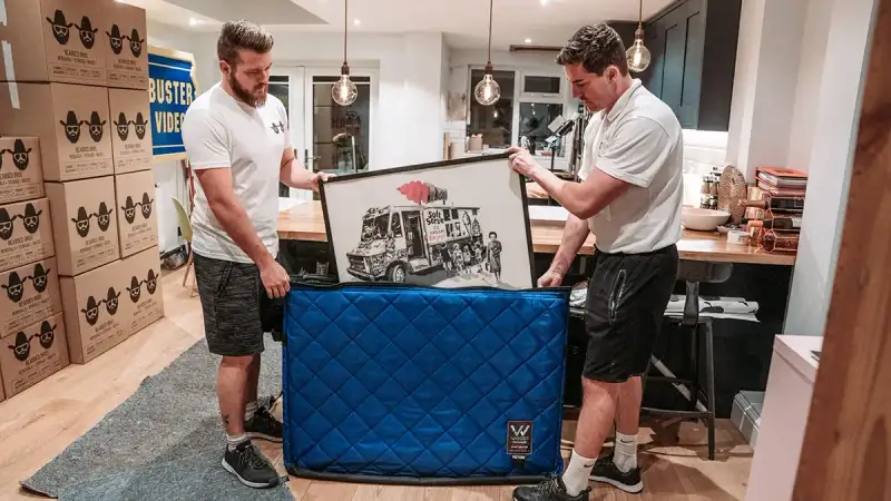 Movers wrapping a framed picture for safe transport, Bearded Bros