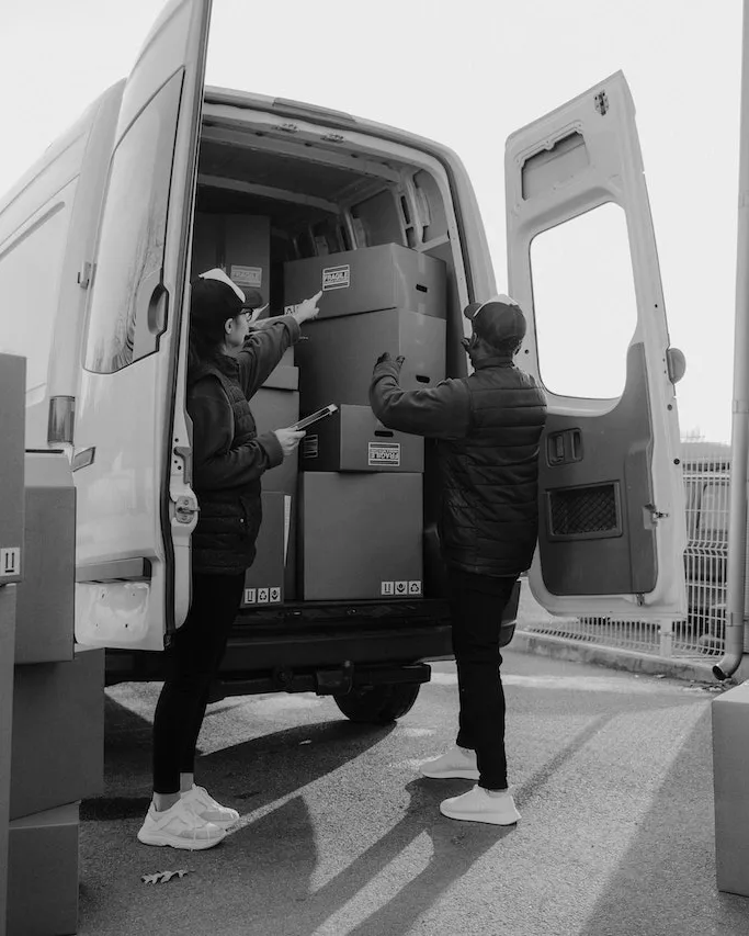 Two people loading fragile-marked moving boxes into a van, Bearded Bros removals