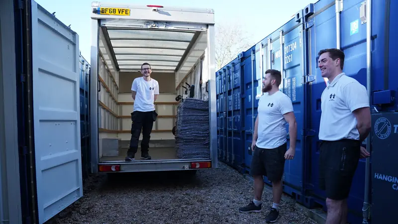 Bearded Bros crew members chatting between storage containers, one stood inside a removals van