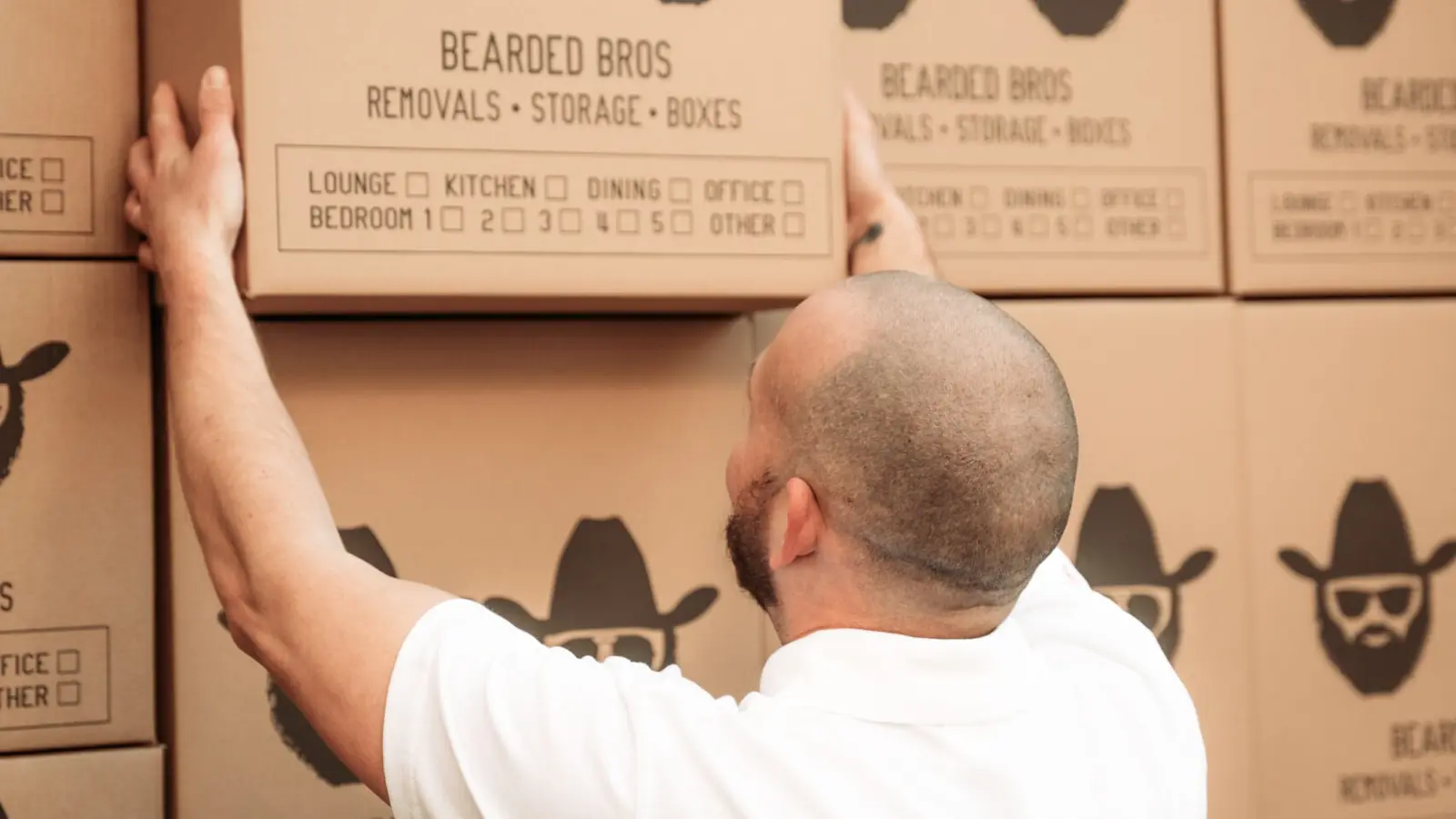 Bearded Bros crew member stacking a branded box against a wall of boxes