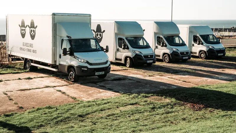 Bearded Bros removals van fleet parked on grass overlooking the Brighton coastline